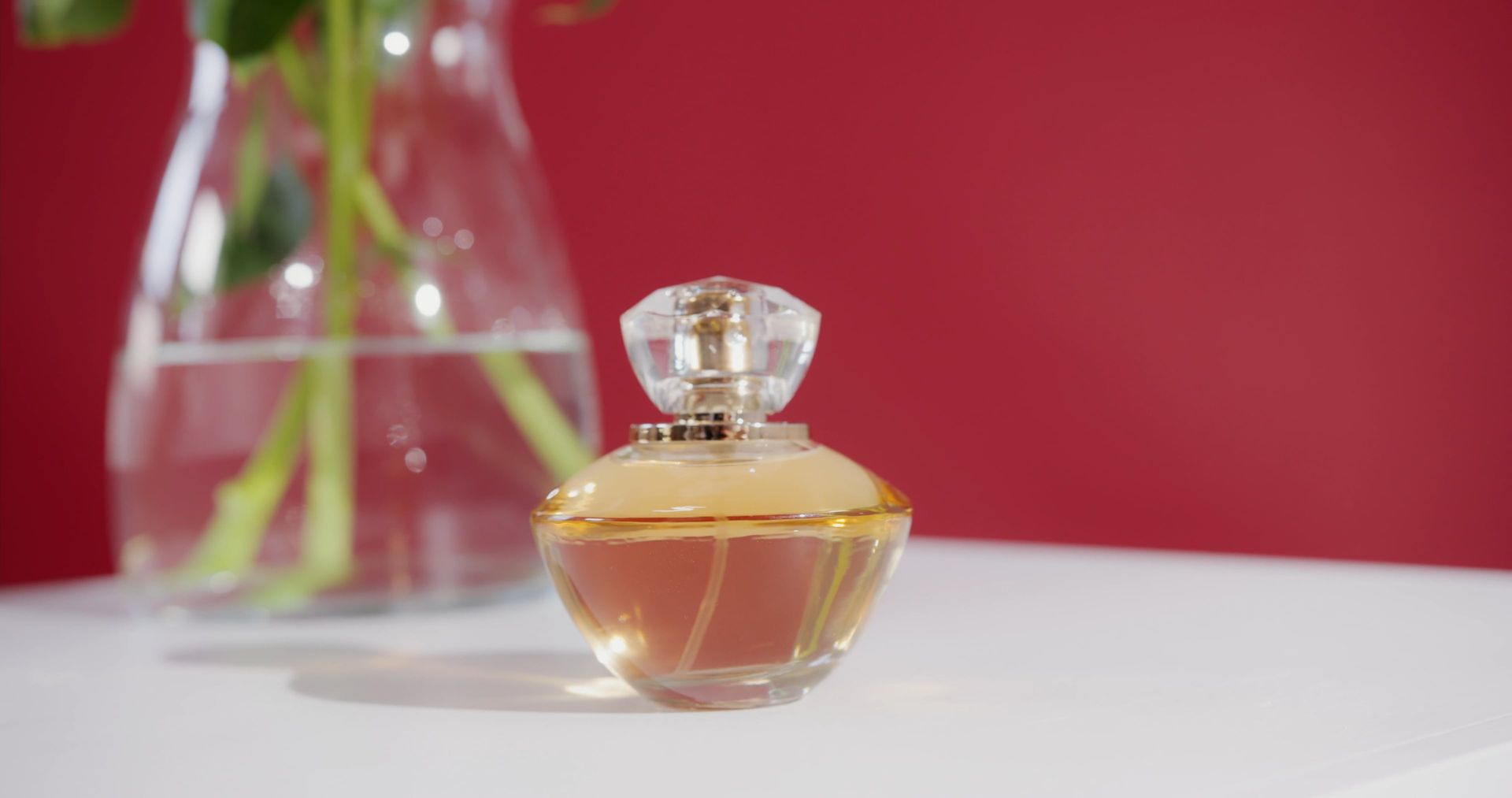 A close-up of a stylish perfume bottle against a vibrant red background, 25s, 16:9