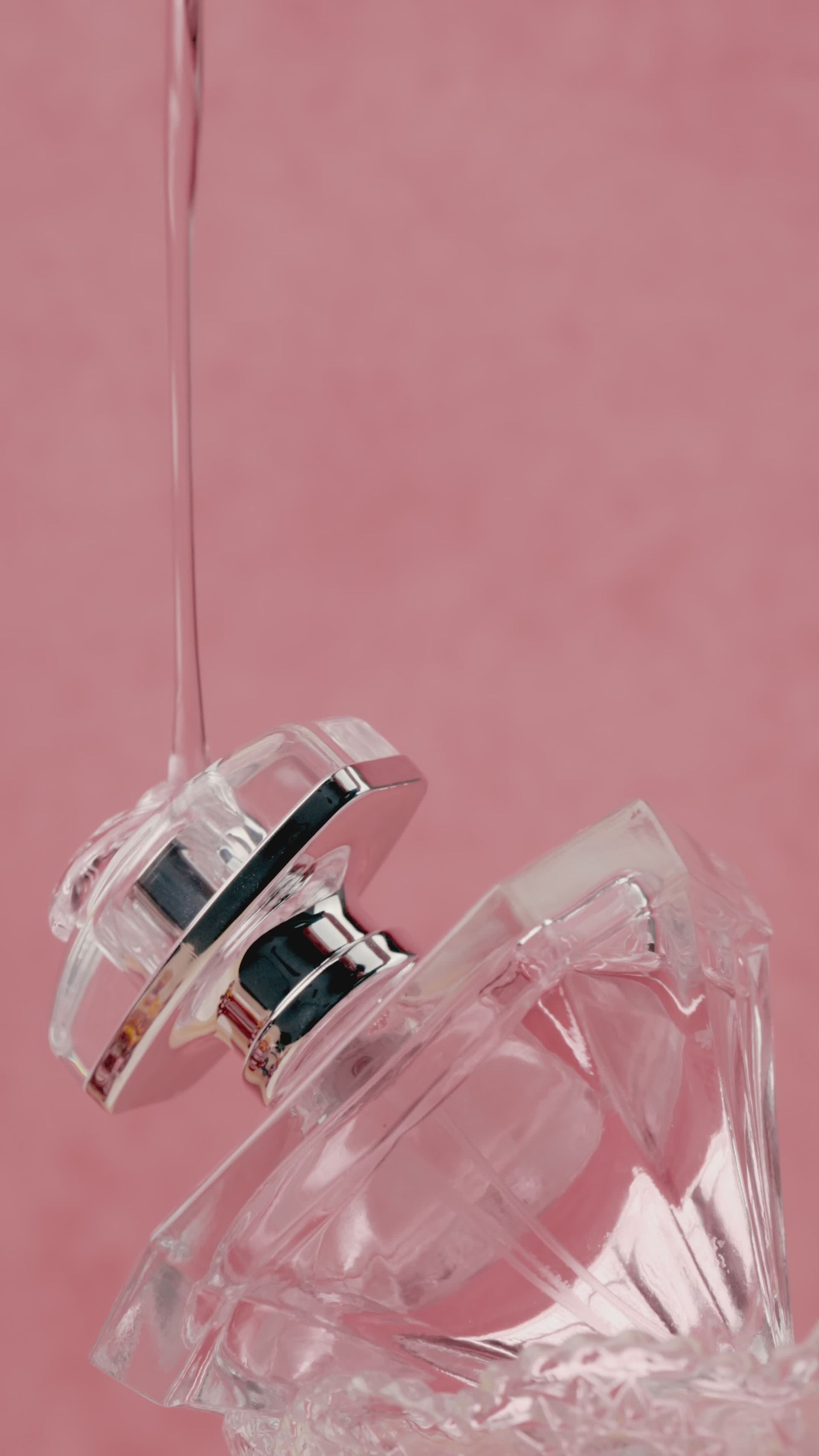 Close-up of perfume bottle with liquid drop on pink backdrop, 23s, 9:16